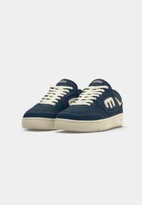 Pair of navy blue and white low-top sneakers with white laces and thick white soles on white background.