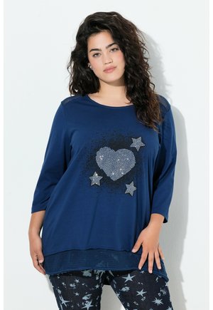 Marineblauwe langemouwen top met een hart- en sterrenpatroon van strass. Kenmerkt zich door een gestructureerde zoom en gaasaccenten op de schouders.