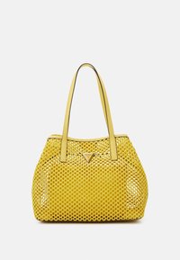 Sac fourre-tout en cuir jaune avec un motif perforé, deux poignées, et un détail de logo triangulaire à l'avant. Texture lisse, forme arrondie.