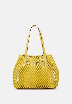 Sac fourre-tout en cuir jaune avec un motif perforé, deux poignées, et un détail de logo triangulaire à l'avant. Texture lisse, forme arrondie.