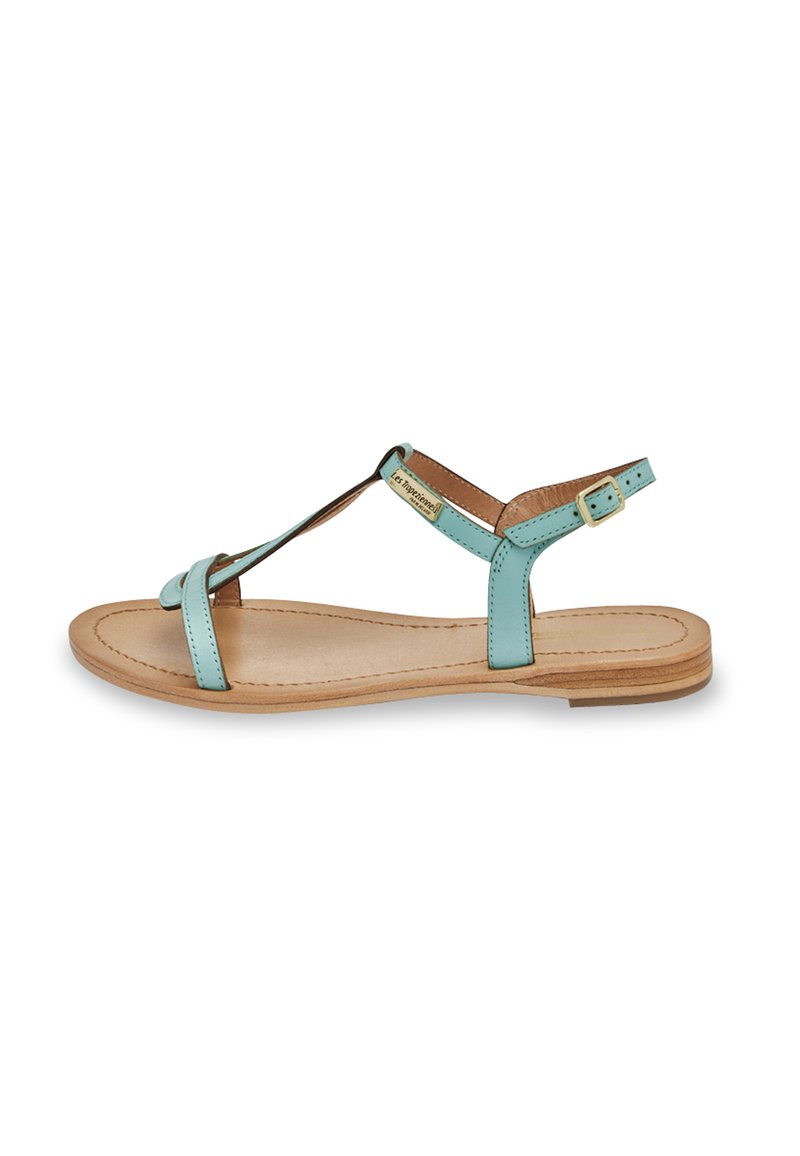 Sandalo in pelle blu chiaro con design a T, suola piatta e cinturino alla caviglia regolabile. Presenta una soletta beige e dettagli hardware minimalisti.