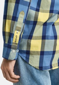 Herren Karohemd in Blau, Gelb und Grün. Besitzt einen Knopfmanschette mit Logo-Stickerei und einen abgerundeten Saum, gefertigt aus einem weichen Baumwollmix.
