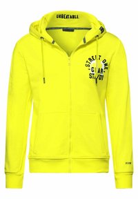 Felpa gialla con zip in morbido tessuto, dotata di cappuccio con coulisse, tasche anteriori e testo stampato nero sul petto.