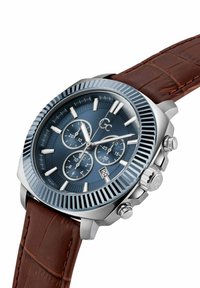 Reloj de acero inoxidable plateado con un dial azul, correa de cuero marrón, tres subdiales y una pantalla de fecha. Cuenta con un bisel texturizado y acentos pulidos.