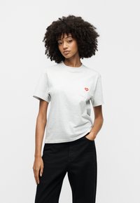 Γκρι βαμβακερό t-shirt με στρογγυλή λαιμόκοψη και κοντά μανίκια, με μικρό κόκκινο καρδιάκι στο αριστερό μέρος της τσέπης στο στήθος.