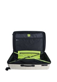 Hard-shell suitcase in off-white, with a black interior. Features bright green dividers and straps, combination lock, and double wheels.