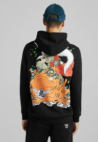 Sudadera negra con capucha que presenta un gráfico vibrante de una rana y dos personajes en la parte trasera, con acentos en azul, verde y naranja, y una textura suave.