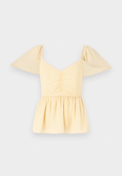 Puff-sleeved peplum top in soft yellow cotton with a gathered bodice and a flared hem, featuring subtle speckles throughout the fabric.