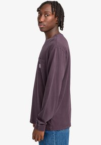 Long-sleeve shirt in dark purple cotton with a front pocket. Features casual design, loose fit, and contrast stitching.