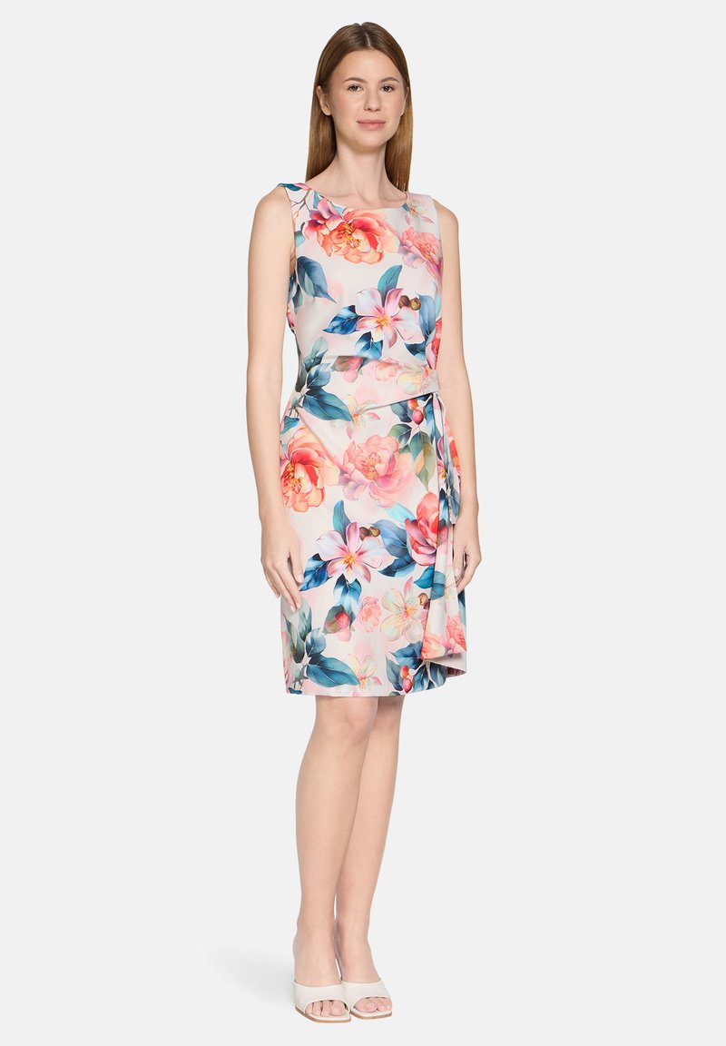 Robe fleurie avec un corsage ajusté, une jupe courte et un détail noué à la taille. Présente des fleurs roses et des feuilles bleues sur un fond clair.