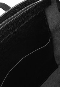 Interno di una borsa in pelle nera, caratterizzato da una superficie testurizzata, una chiusura con zipper e un dettaglio di cucitura di colore chiaro a contrasto.