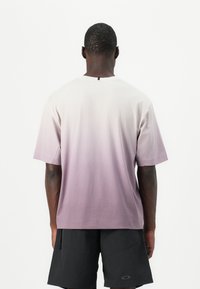 T-Shirt mit einem Farbverlauf von helllila zu dunkel lila, Kurzarm und rundem Ausschnitt. Der Stoff wirkt weich und hat eine lässige Passform.