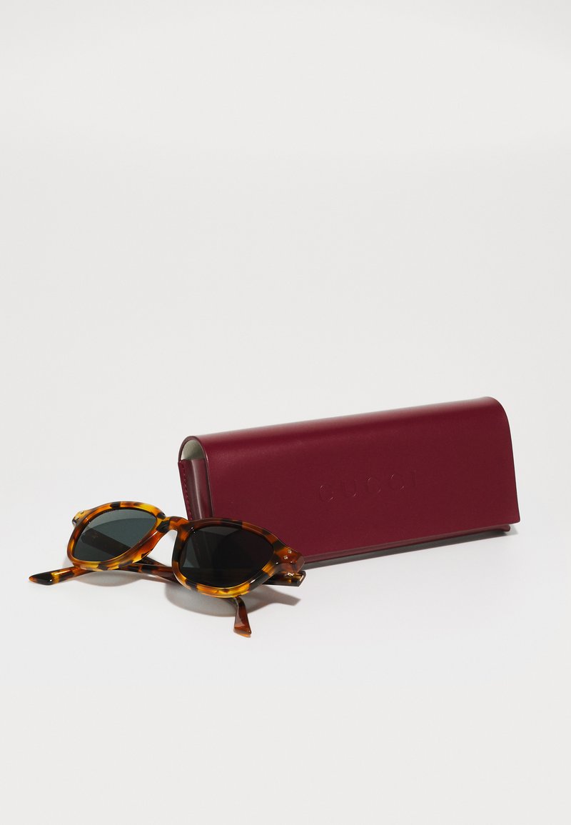 Schildpadbril met zwarte lenses en ronde monturen, vergezeld van een bordeaux rectangular etui met de ingedrukte merknaam.