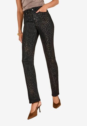 Schwarze Jeans mit einem subtilen Leopardenmuster, hoher Taille und schmaler Passform, kombiniert mit braunen Absatzschuhen.