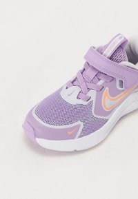 Lila Sportschuh mit Netz-Obermaterial, elastischen Schnürsenkeln und verstellbarem Riemen. Auffälliger orangefarbener Nike-Swoosh und Akzente an den Seiten und der Zunge.