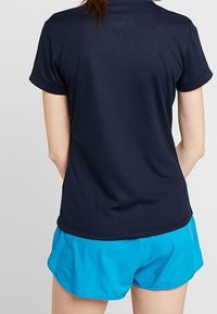 Marinblå t-shirt med kort ärm och en figursydd design, kombinerad med ljusblå atletiska shorts, som har en mjuk textur och en avslappnad passform.