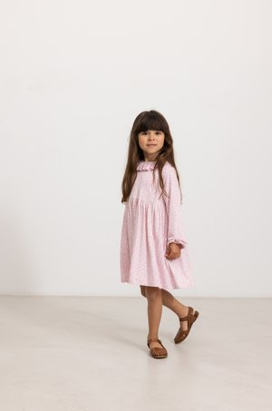 Abito rosa chiaro con maniche lunghe, colletto arricciato e motivo floreale. Sandali marroni con un design intrecciato. Vestibilità semplice e casual.