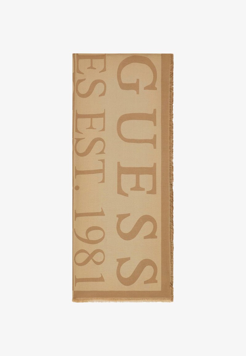 Écharpe beige avec de grandes lettres couleur taupe indiquant "GUESS EST. 1981" et bords à franges sur fond blanc.