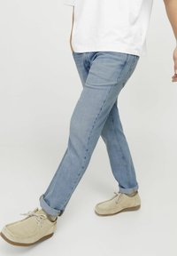 Svetlo modri denim nabori s ozkim krojem, zavihanimi robovi in svetlosemimi rjavimi vsakodnevnimi čevlji. Obleka je kombinirana s preprosto belo majico.