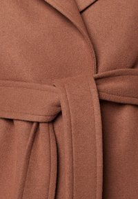 Brązowy wełniany płaszcz z paskiem, charakteryzujący się miękką teksturą, kołnierzem z wycięciem oraz rozszerzanym krojem. Pasek jest szeroki, podkreślając talię.