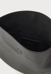 Μαύρη δερμάτινη τσάντα με ομαλή υφή· διαθέτει στρογγυλό κούμπωμα με πάτημα και εσωτερική ετικέτα με χρυσό κείμενο. Απλός σχεδιασμός τύπου κουβά.