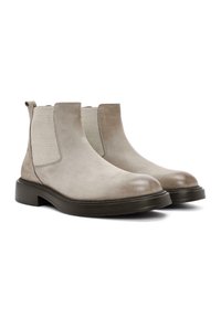 Botas Chelsea de ante beige con paneles laterales elásticos, punteras redondeadas y suelas de goma negra gruesa. Incluyen tiradores para facilitar su colocación.