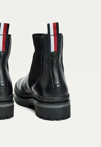Schwarze Leder-Stiefeletten mit elastischen Seiten, strukturiertem Finish und Gummisohlen. Mit einem gestreiften Zugband und Logo an der Seite.