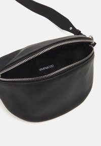 Borsa in pelle nera con forma arrotondata, chiusura con zip argentata e interno foderato in tessuto. L'etichetta interna riporta la scritta "even&odd."