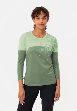 Lichtgroen langblijvend shirt met een gestructureerd bovenstuk dat een driehoekig patroon heeft en een effen donkerder groen onderstuk.