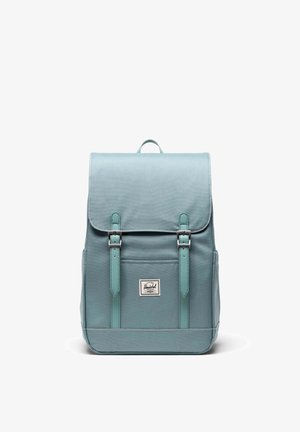 Tyrkysový batoh z látky má klopu so zapínaním na dve nastaviteľné remene, predné vrecko a značkovú nášivku. Hladká textúra so šitými akcentmi.