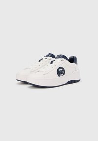 Biele tenisky s námorníckymi akcentmi, s okrúhlym logom na boku, okrúhlymi šnúrkami a hrubou platformovou podrážkou pre väčšiu výšku.