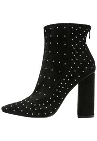 Schwarzer Wildleder-Stiefelette mit spitz zulaufender Zehe und Blockabsatz, verziert mit silbernen Nieten, die entlang der Seiten in einem gepunkteten Muster angeordnet sind.