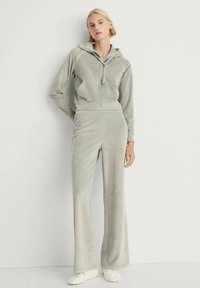 Light gray velour tracksuit with a zip-up hooded top, two front pockets, and wide-leg pants. Soft texture and clean design lines.