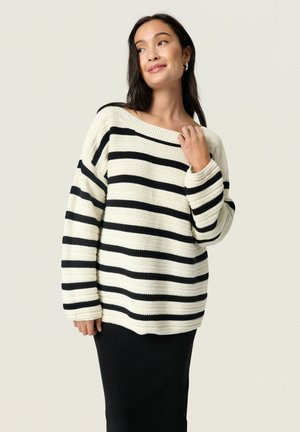 Sort og hvid stribet sweater med en løs pasform, bred bådudskæring og ribbede manchetter, parret med en sort ribbet nederdel.