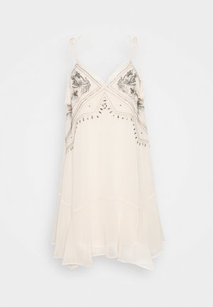 Mouwloze witte jurk met fijne borduurdetails, kralenaccenten en een vloeiende zoom. Voorzien van verstelbare bandjes en een V-hals ontwerp.