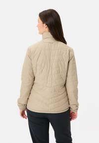 Lichtbeige gewatteerde jas met een hoge kraag, elastische manchetten en een getailleerd ontwerp, die een gladde, gestructureerde oppervlakte toont.