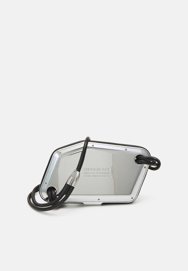 Metallic silver bag with an angular shape, featuring a black strap and engraved details on the surface. Smooth texture with a reflective finish.