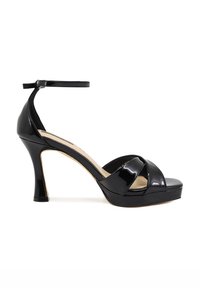 Sandalo con tacco alto in pelle verniciata nera, punta rotonda, design con cinturino incrociato, cinturino alla caviglia e un tacco solido e affusolato.