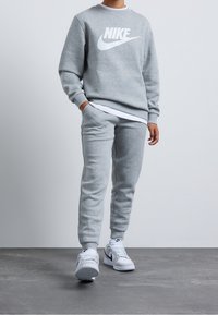 Nike Sportswear CLUB UNISEX - Träningsbyxor - dark grey heather/base grey/white