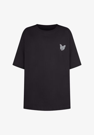 T-shirt noir oversize en coton, avec un petit graphique de papillon argenté sur la gauche de la poitrine. Encolure ras du cou standard.