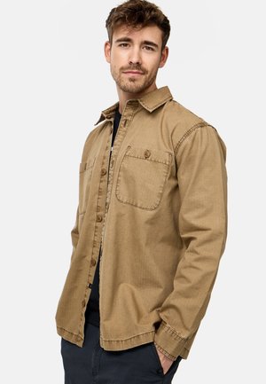 Light brown button-up shirt with a textured fabric, chest pockets, and a collar. Features a relaxed fit and buttons in front.