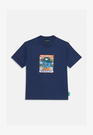 Tengerészkék rövid ujjú póló, rajta egy grafika egy kék medvéről, aki zöld sapkát és narancssárga mellényt visel, azzal a felirattal, hogy "Manga Bear Crew" és "Emporio Armani."