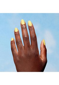 Mano con cinque dita con smalto giallo sulle unghie lunghe e a mandorla; pelle di colore marrone scuro con texture visibile. Sfondo blu chiaro.