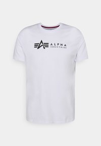 Hvid bomulds t-shirt med et sort logo, der har stiliserede bogstaver "A" og "ALPHA INDUSTRIES" trykt på forsiden. Korte ærmer, rund halsudskæring.
