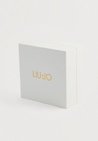 Bielo textúrované štvorcové políčko so zlatým logom "LIU·JO" umiestneným v strede na prednej strane, nafotené na bielom pozadí.