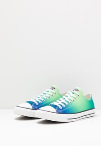 Green and blue gradient canvas sneakers with white rubber soles, featuring white laces and black stripe accents. Classic low-top design.