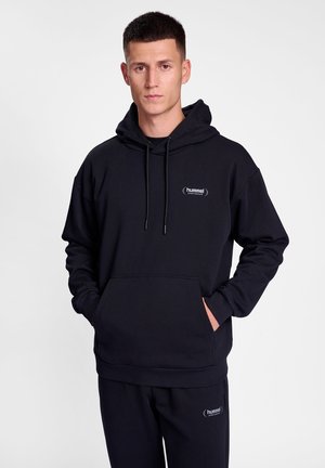 Black hoodie made of soft fabric, featuring a kangaroo pocket, adjustable drawstring hood, and a small embroidered logo on the chest.