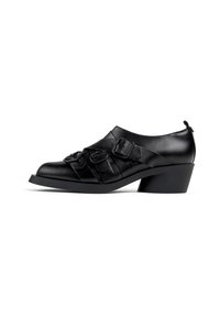 Zapato de cuero negro con punta redonda, que presenta hebillas decorativas y acentos plisados. El tacón es corto y de forma cuadrada.