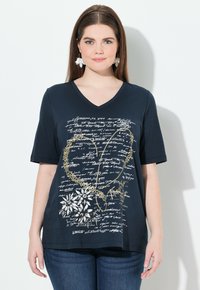 Camiseta de cuello en V azul marino con mangas cortas, que presenta diseños florales y de escritura en blanco y dorado, hecha de una tela suave y lisa.