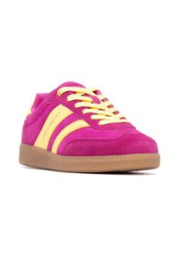 Baskets sportives avec une tige en daim rose vif et des accents jaunes, des lacets et une semelle en caoutchouc. Design bas classique avec des rayures.
